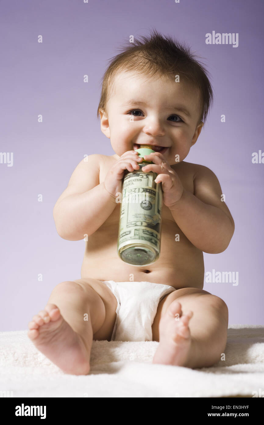 Baby drinking from bottle with US currency in it Stock Photo
