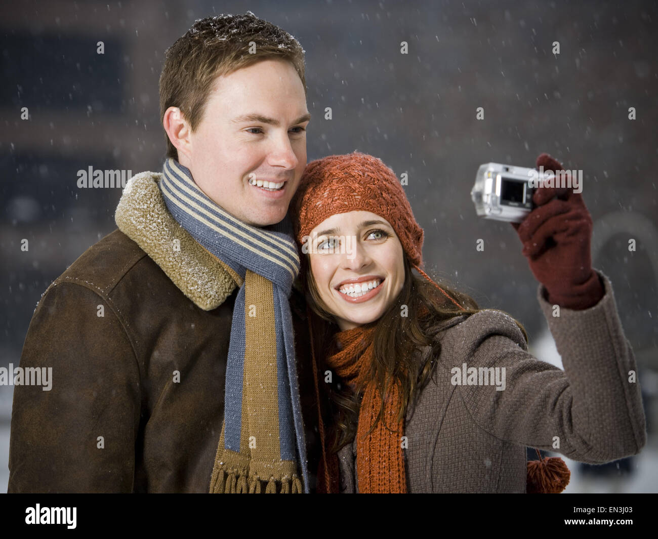 Man and woman taking a photo outdoors in winter Stock Photo