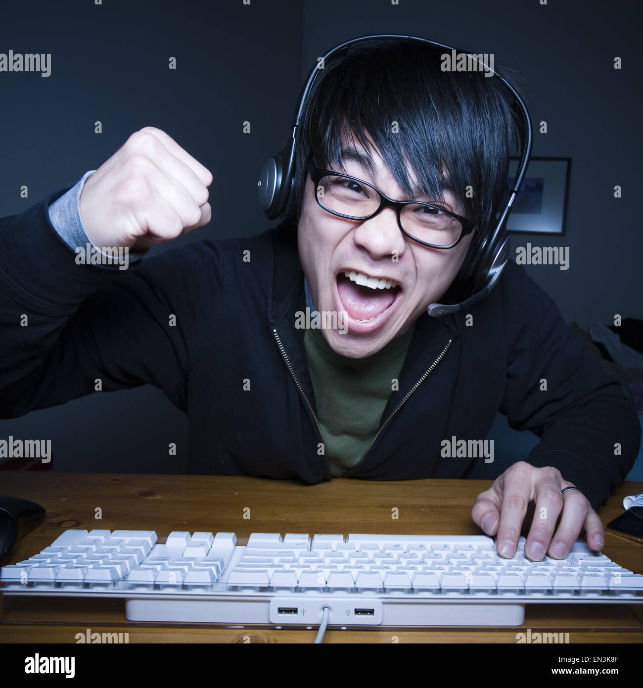 Man with headset making fists and sitting at keyboard Stock Photo