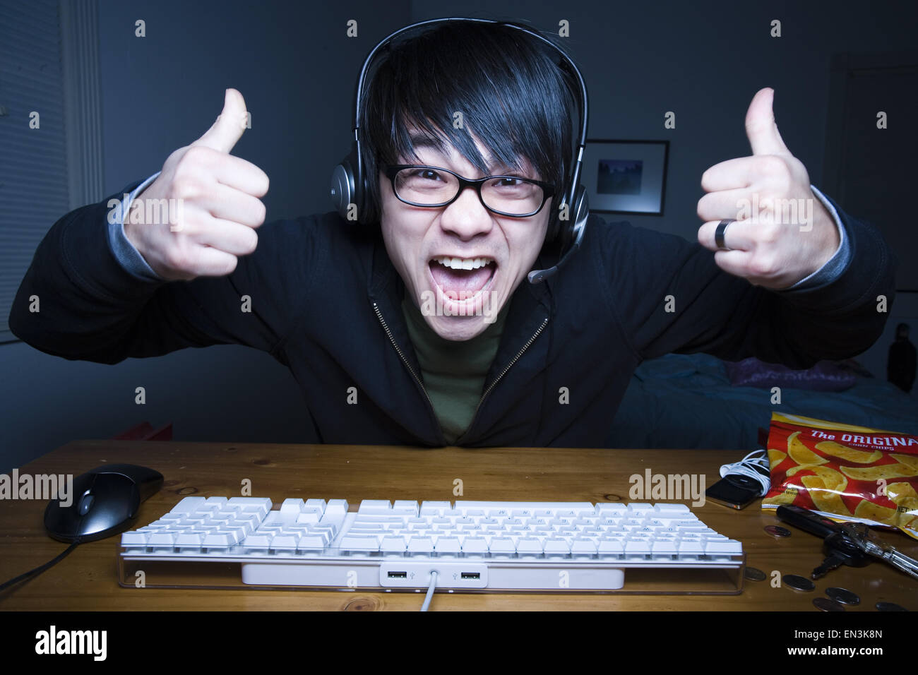 Man with headset making fists and sitting at keyboard Stock Photo