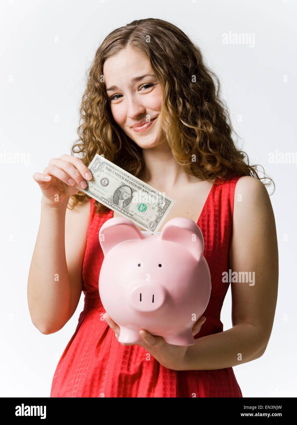 woman putting a dollar in a piggybank Stock Photo