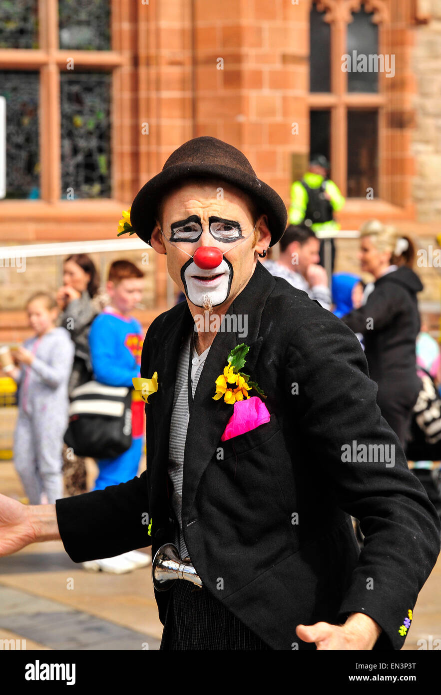 Clown with painted face and red nose wearing a hat in the Guildhall Square, Derry, Londonderry, Northern Ireland. Stock Photo