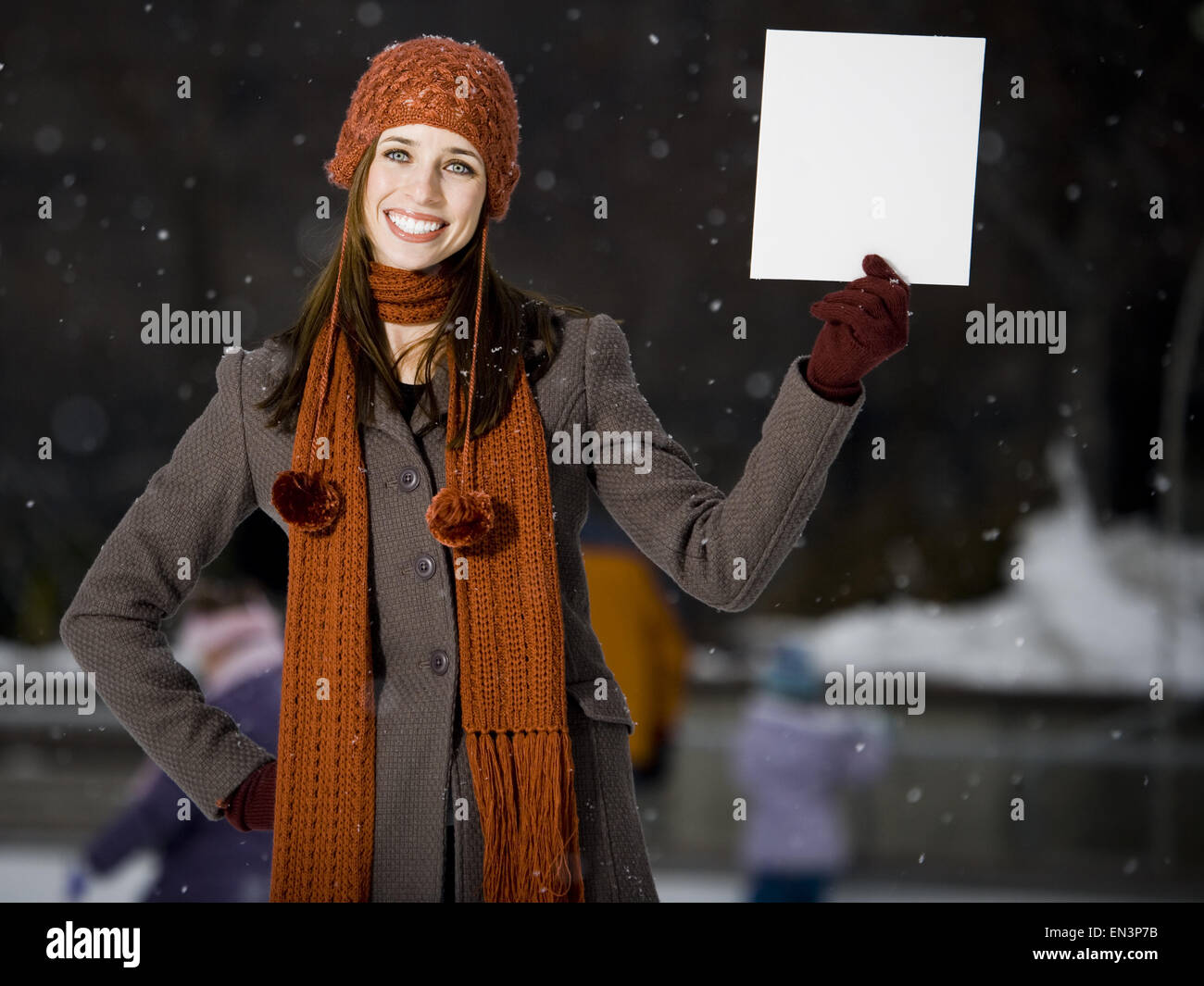 Woman with skates holding blank sign outdoors in winter Stock Photo