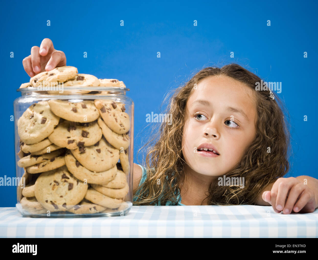 Girl taking chocolate chip cookie from jar Stock Photo