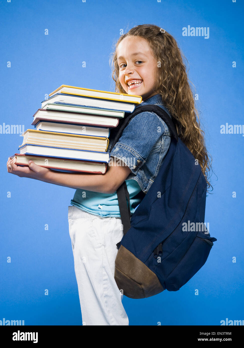 Smiling girl with backpack carrying pile of textbooks Stock Photo - Alamy