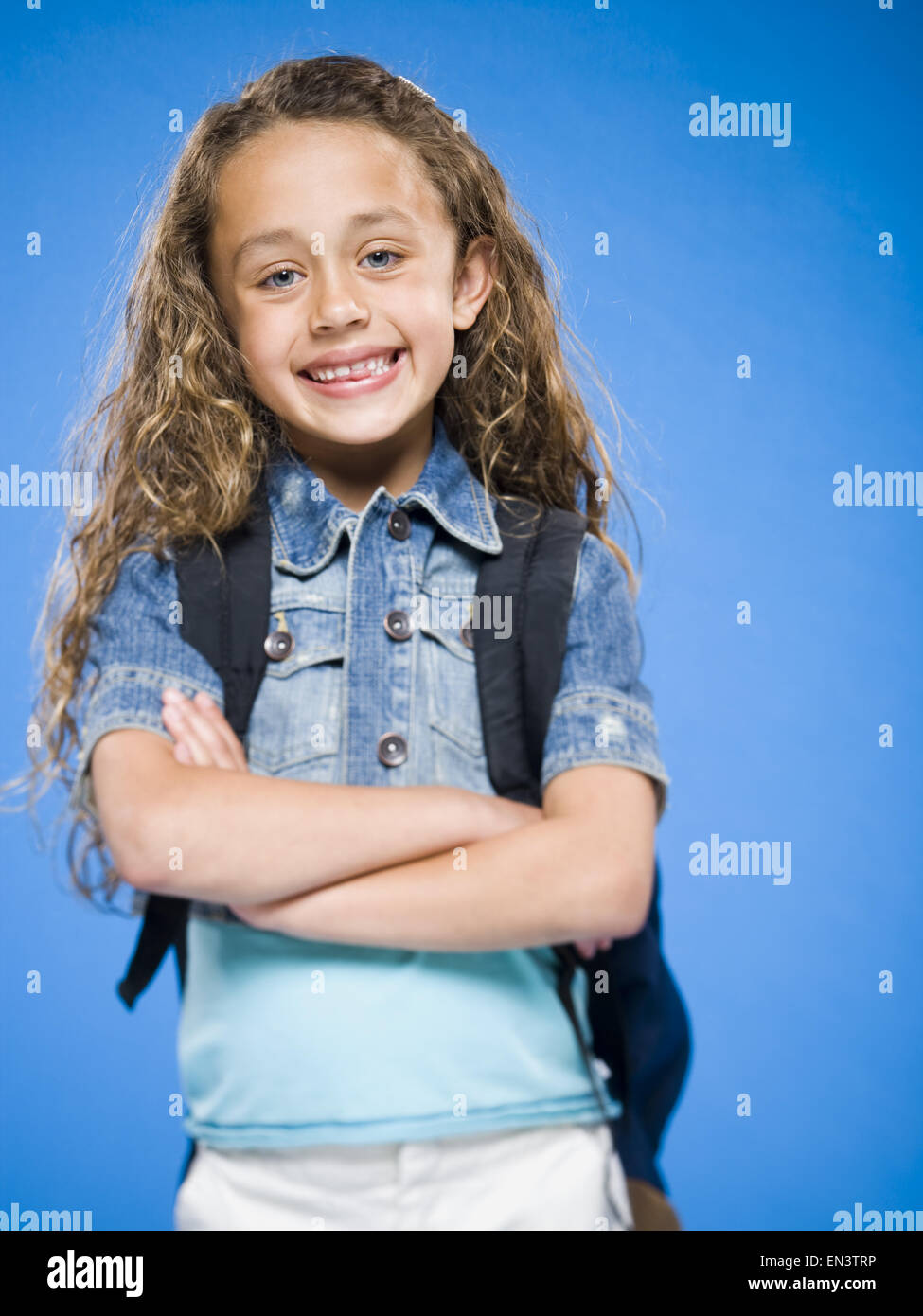 Smiling girl with arms crossed and backpack Stock Photo - Alamy