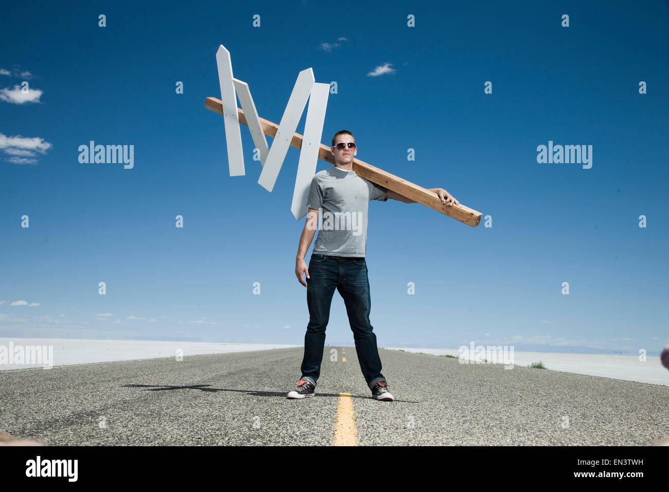 man holding a direction sign in the middle of the road Stock Photo