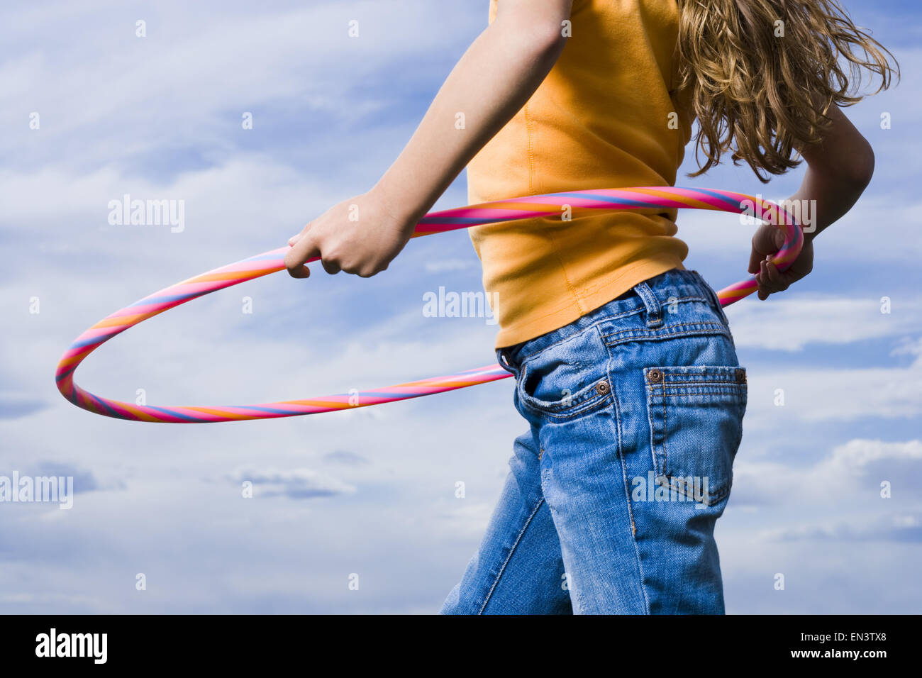 Mid section view of girl with hula hoop outdoors with clouds Stock Photo