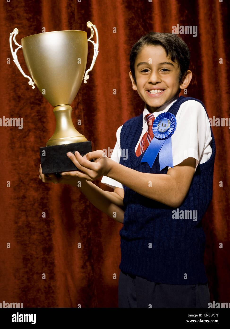 Boy with blue ribbon and trophy cup smiling Stock Photo Alamy