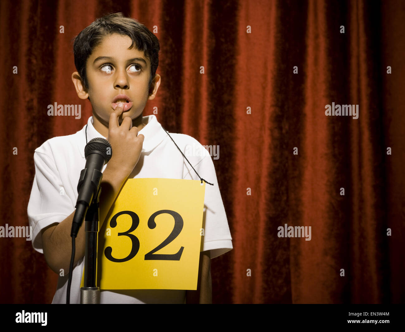Boy contestant standing at microphone thinking Stock Photo