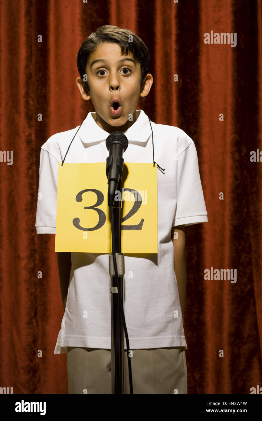 Boy standing at microphone speaking with number around neck Stock Photo