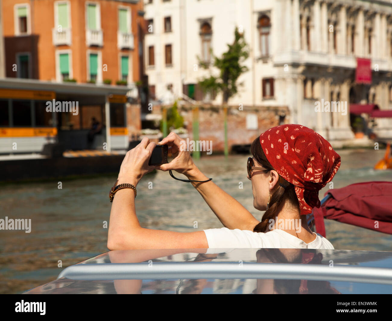 Italy, Venice, Mature woman taking photographs while traveling on canal Stock Photo