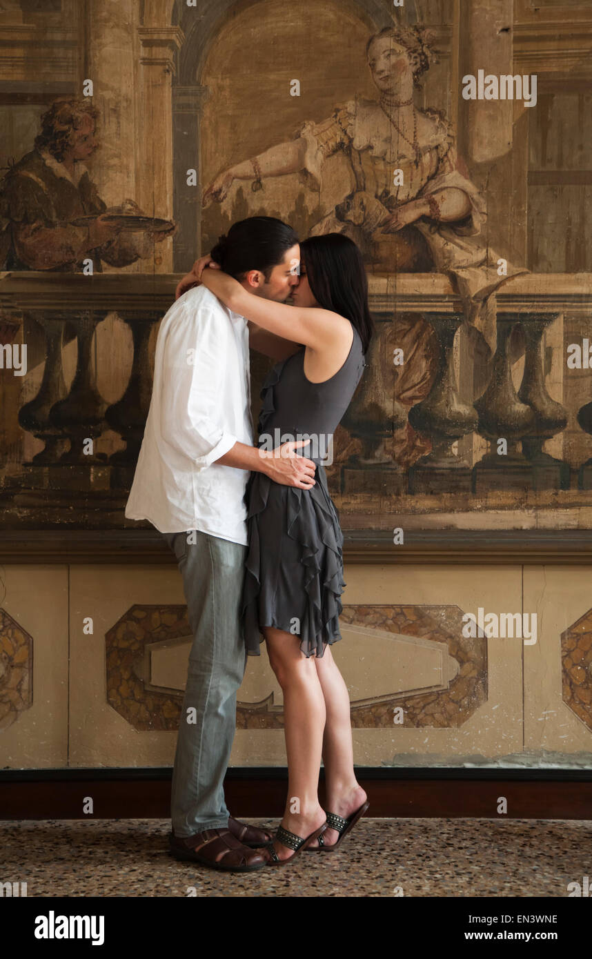 Italy, Venice, Young couple kissing in front of wall painting Stock Photo