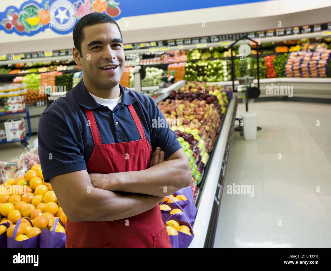 Man with apron in grocery store with arms crossed Stock Photo Alamy