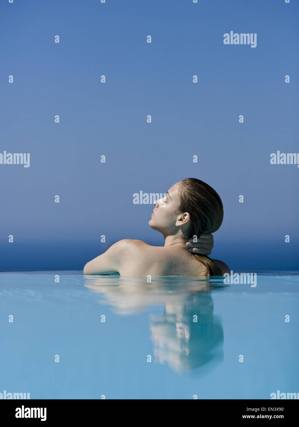 Rear view of woman in pool with eyes closed leaning Stock Photo