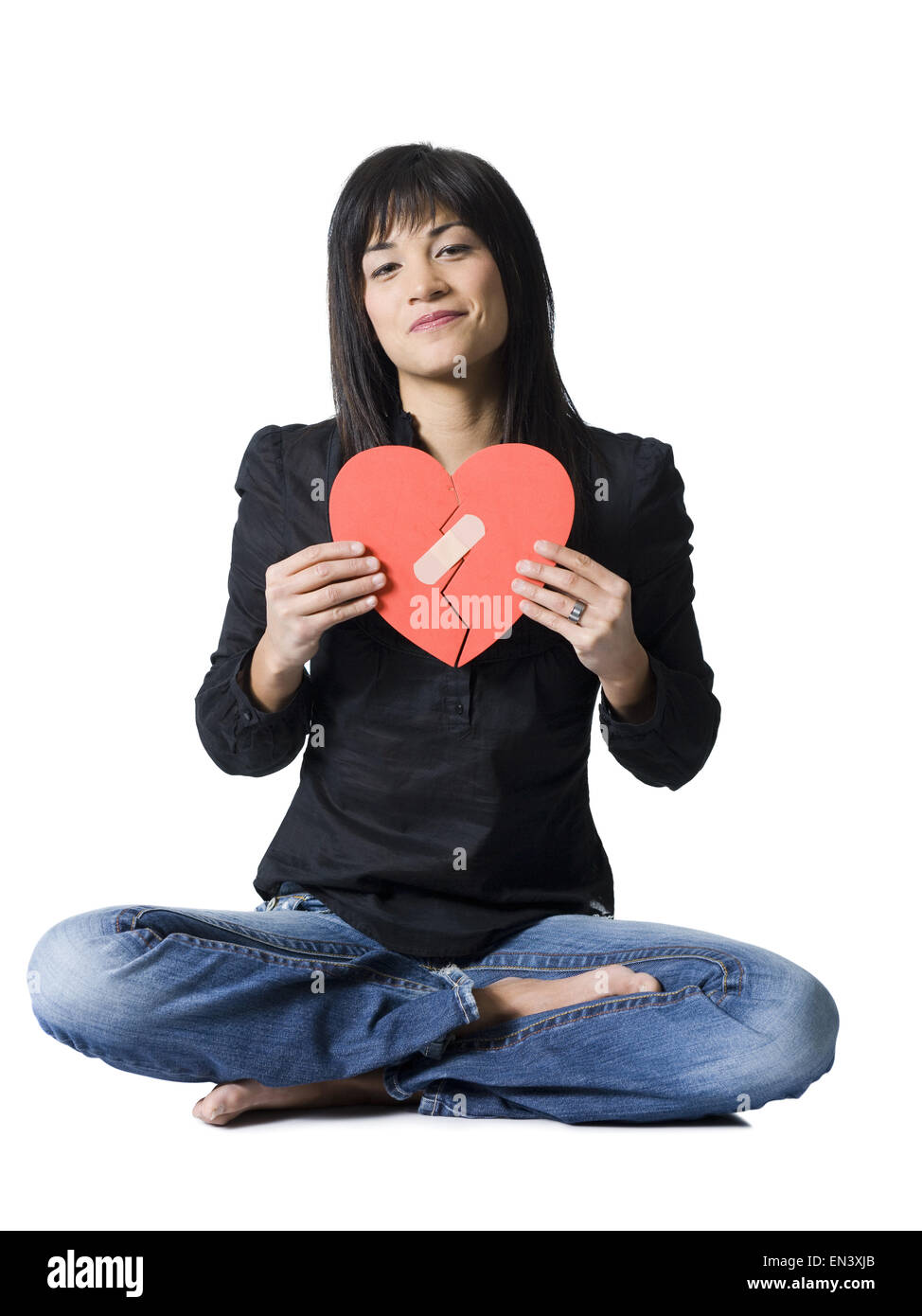 Woman sitting cross legged with mended red heart smiling Stock Photo