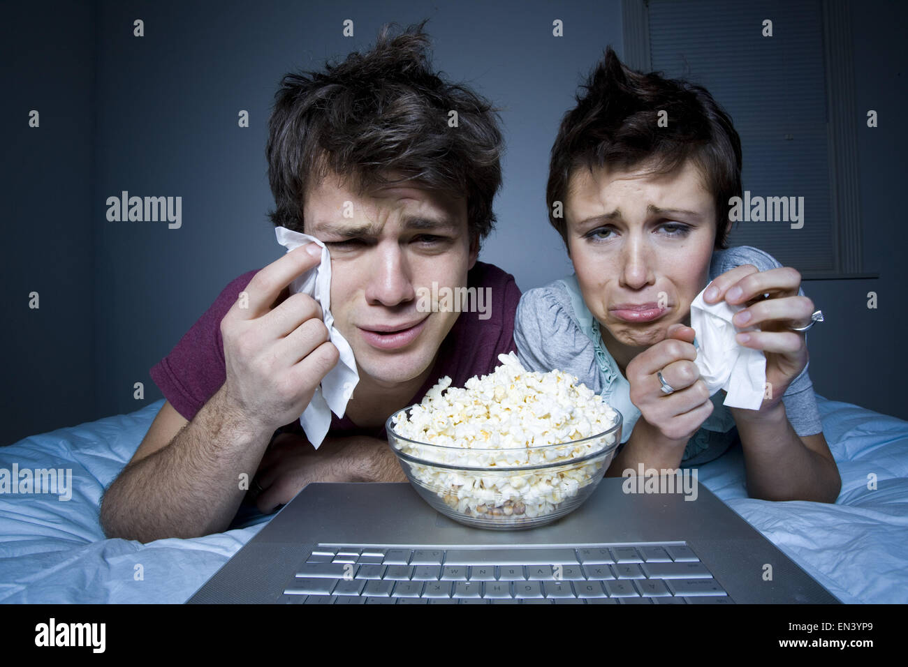 Couple crying with tissue and bowl of popcorn Stock Photo
