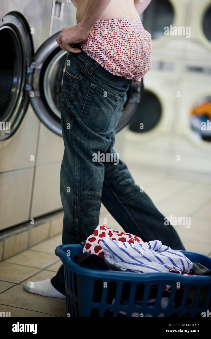man putting on jeans at the laundromat Stock Photo