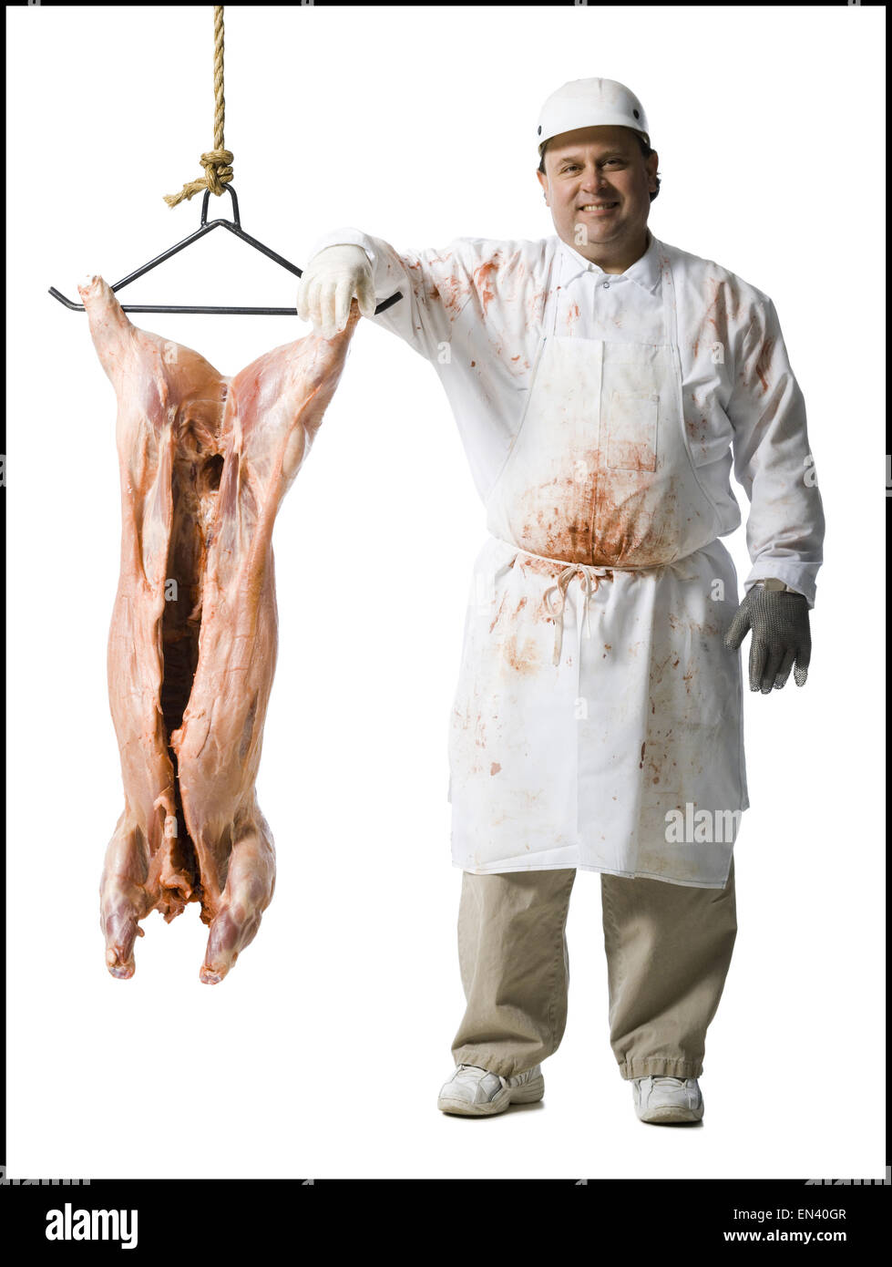Butcher standing with hanging carcass and knife Stock Photo
