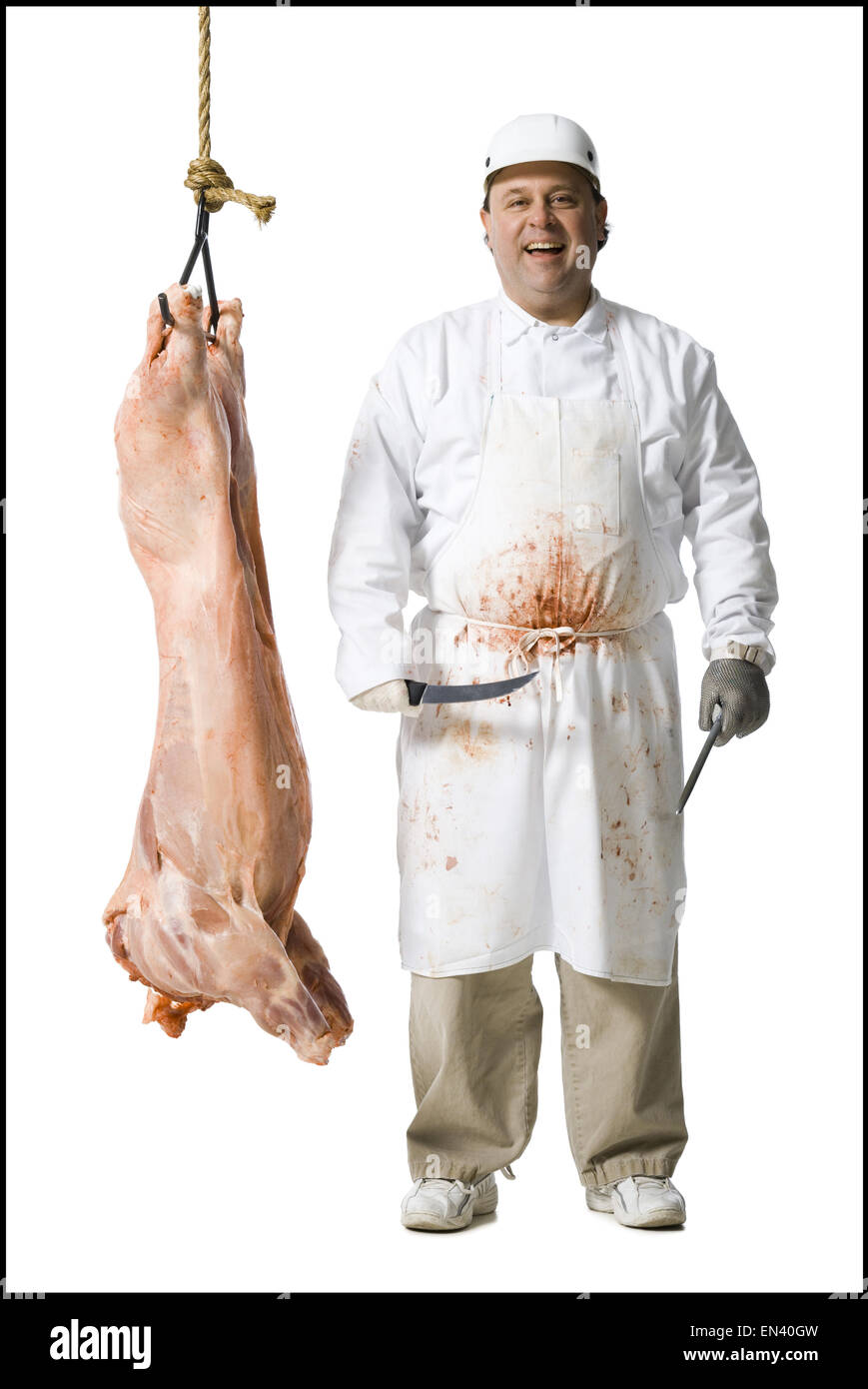 Butcher standing with hanging carcass and knife Stock Photo