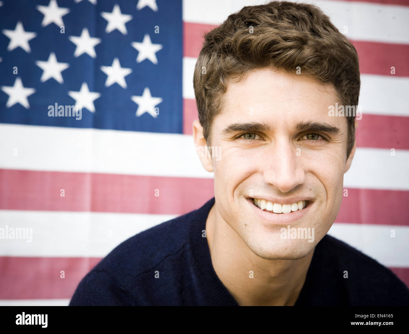 young man smiling in front of an american flag Stock Photo - Alamy