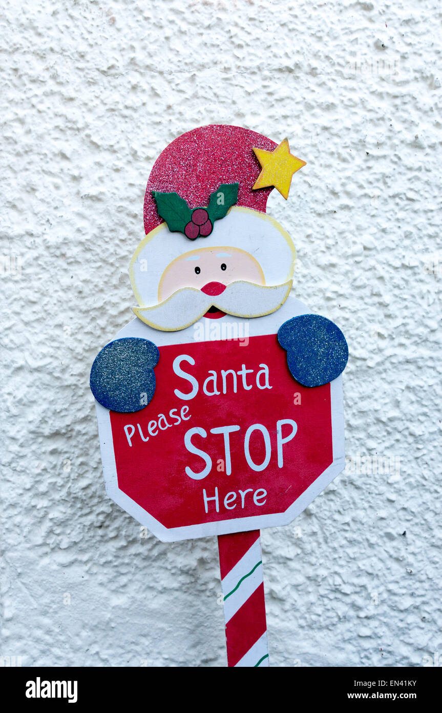 Small Santa Clause figure with sign saying Santa please stop here put  outside of a house at Christmas Stock Photo - Alamy