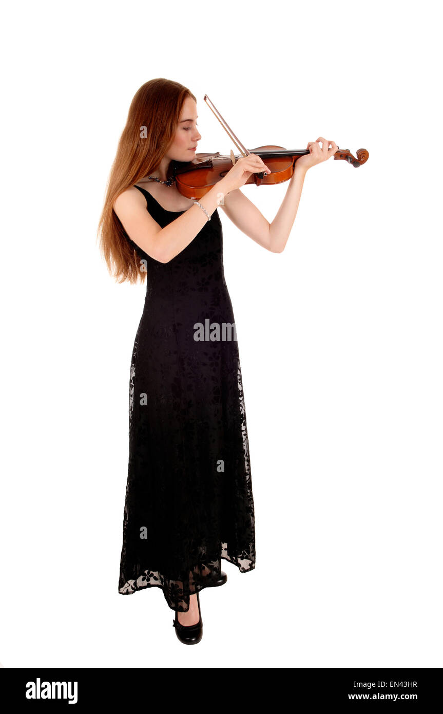 A slim young woman in a long black dress standing for white background ...