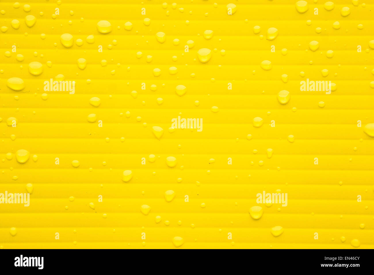 Drops of water from rain on a yellow plastic surface Stock Photo