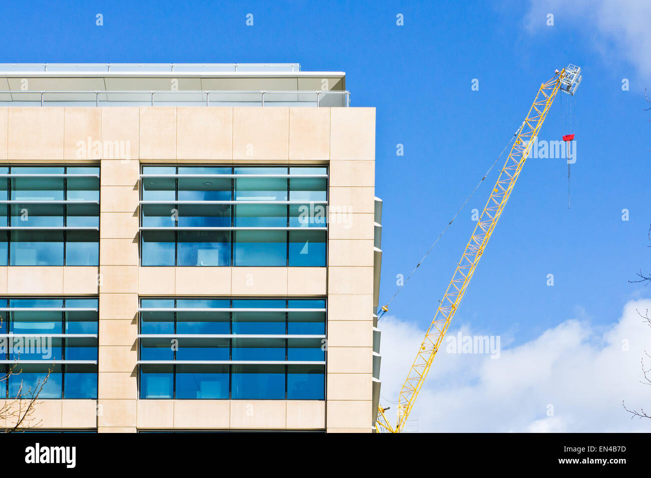 A modern building in the UK with a yellow crane in the background Stock Photo