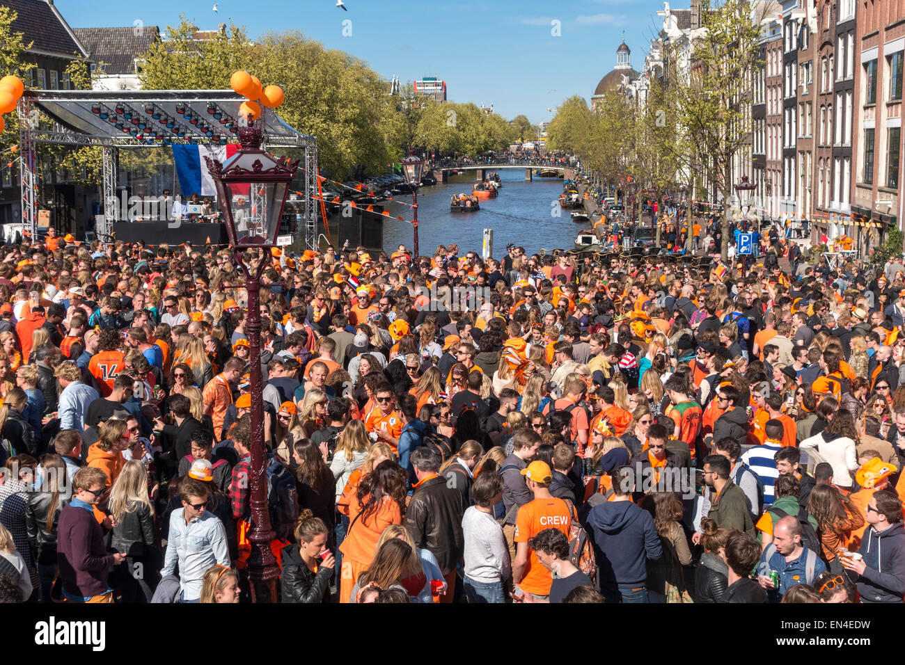 Amsterdam Koningsdag on the Torensluis Bridge on the Singel Canal with a partying crowd on a sunny King's Day. Stock Photo
