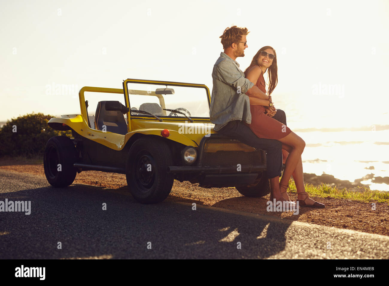 Loving young couple sitting on the hood of their car while out on a