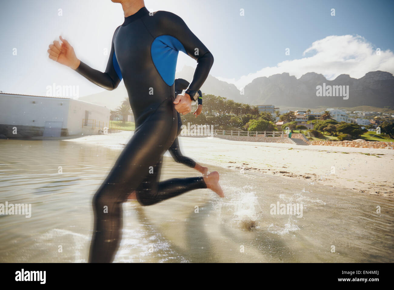 Image of two triathletes rushing into the water. Athlete running into the water, training for a triathlon. Stock Photo