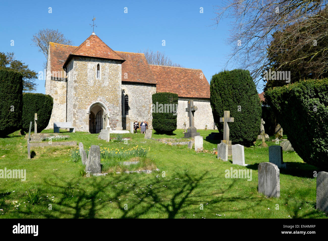 Two senior citizens sit outside the parish church of St Andrew's, West Stoke, West Sussex, England Stock Photo