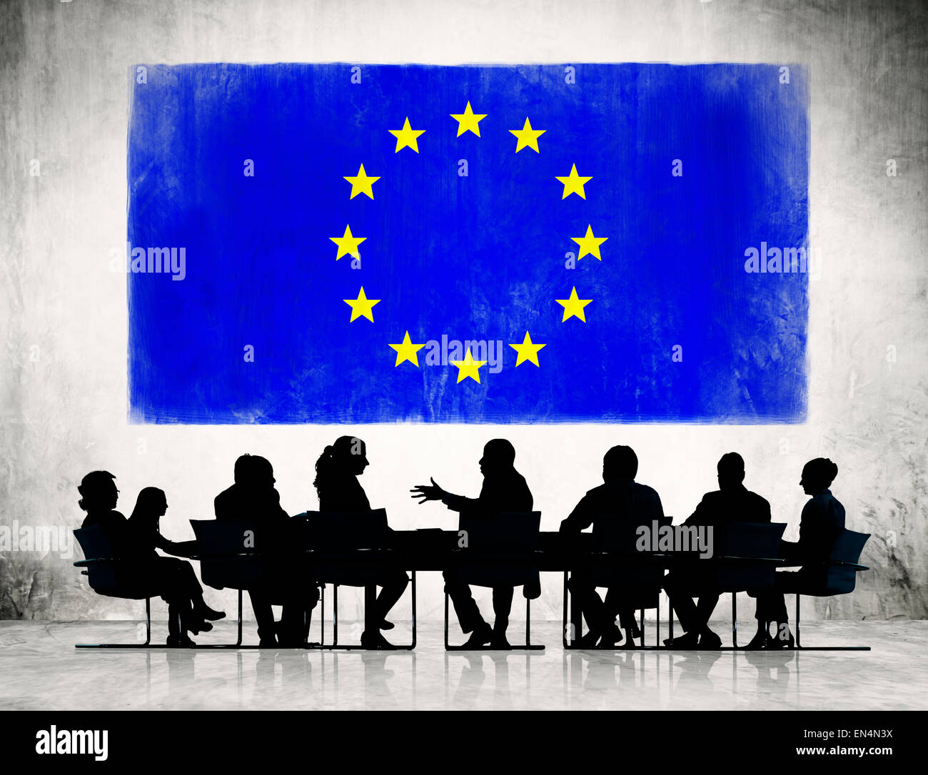 Business People Discussing Around The Conference Table And A Flag Of European Union Above Stock Photo