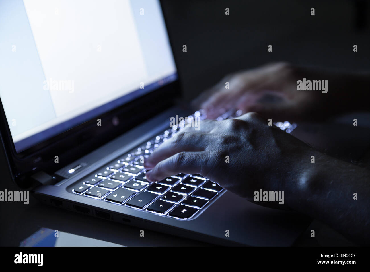 hacker on laptop in dark room Stock Photo