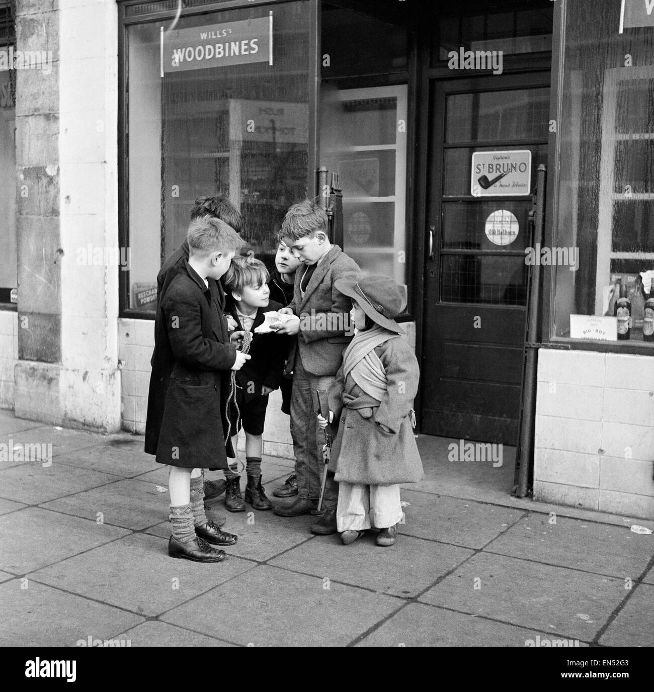 Life in the Mirror Our Gang. 19th January 1954  A gang of boys plot todays agenda of mischief and mayhem outside a tobacconist in Bow Road in the East End of London *** Local Caption *** This is The Conference. Not the stiff necked, prim and tight lipped Stock Photo