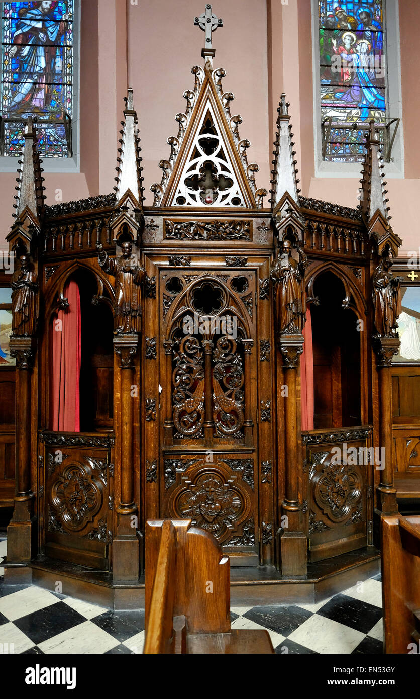 Carved oak confessional boxes dark wood Saint Peter and Paul's Church Cork City. Stock Photo