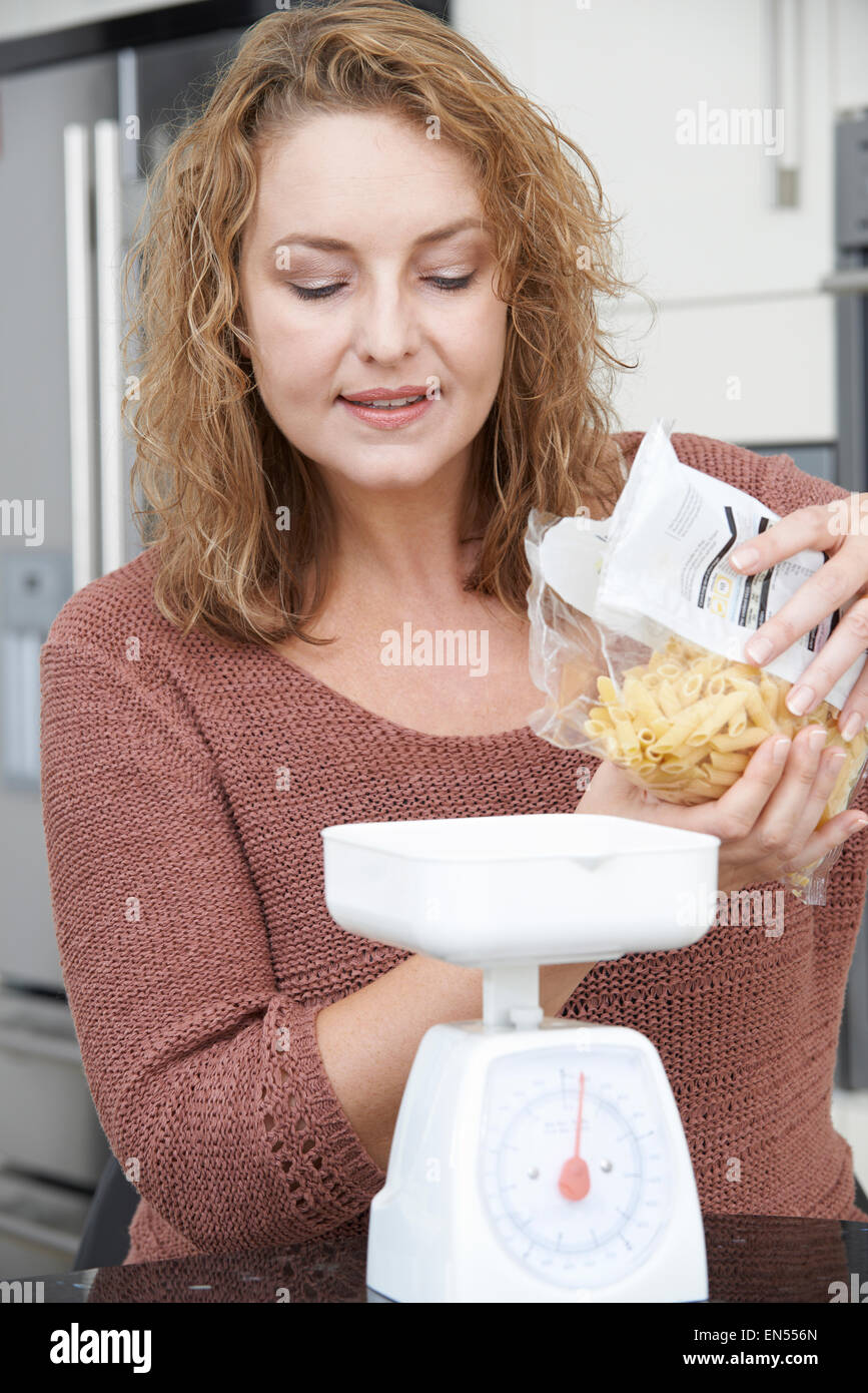 Plus Size Woman On Diet Weighing Out Pasta For Meal Stock Photo