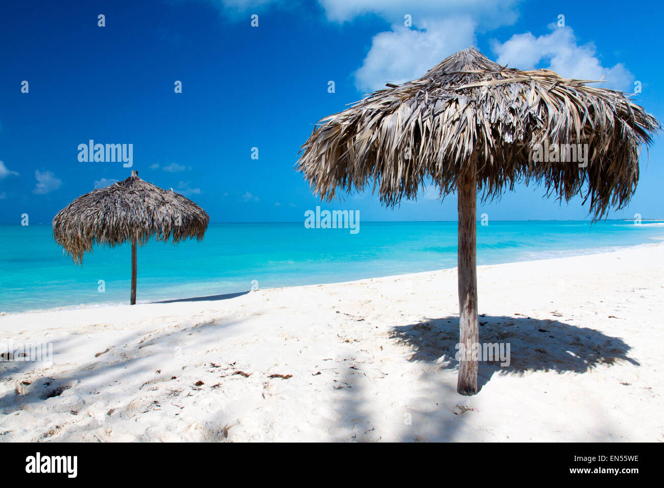 Beach Umbrella made of palm leafs on a perfect white beach in front of Sea. The right place for relax and vacations Stock Photo