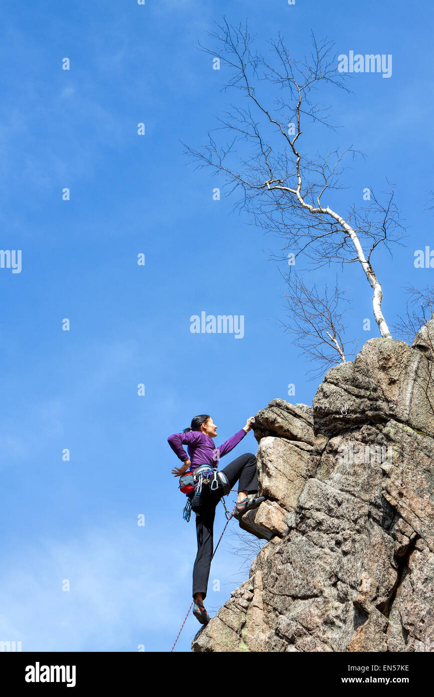 Female happy rock climber on a steep cliff. Stock Photo