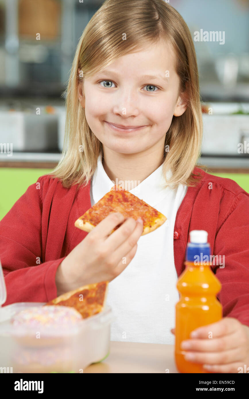 Girl Sitting At Table In School Cafeteria Eating Unhealthy Packed Lunch Stock Photo