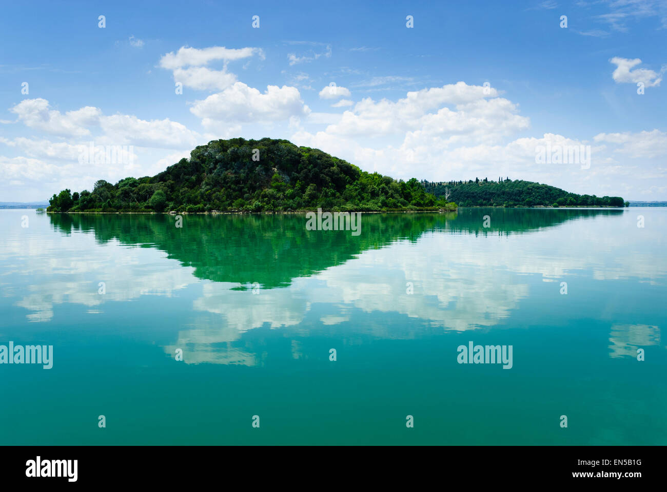 Reflection of Isola Maggiore and Minore and summer sky  in still waters of Lake Trasimeno Italy Stock Photo