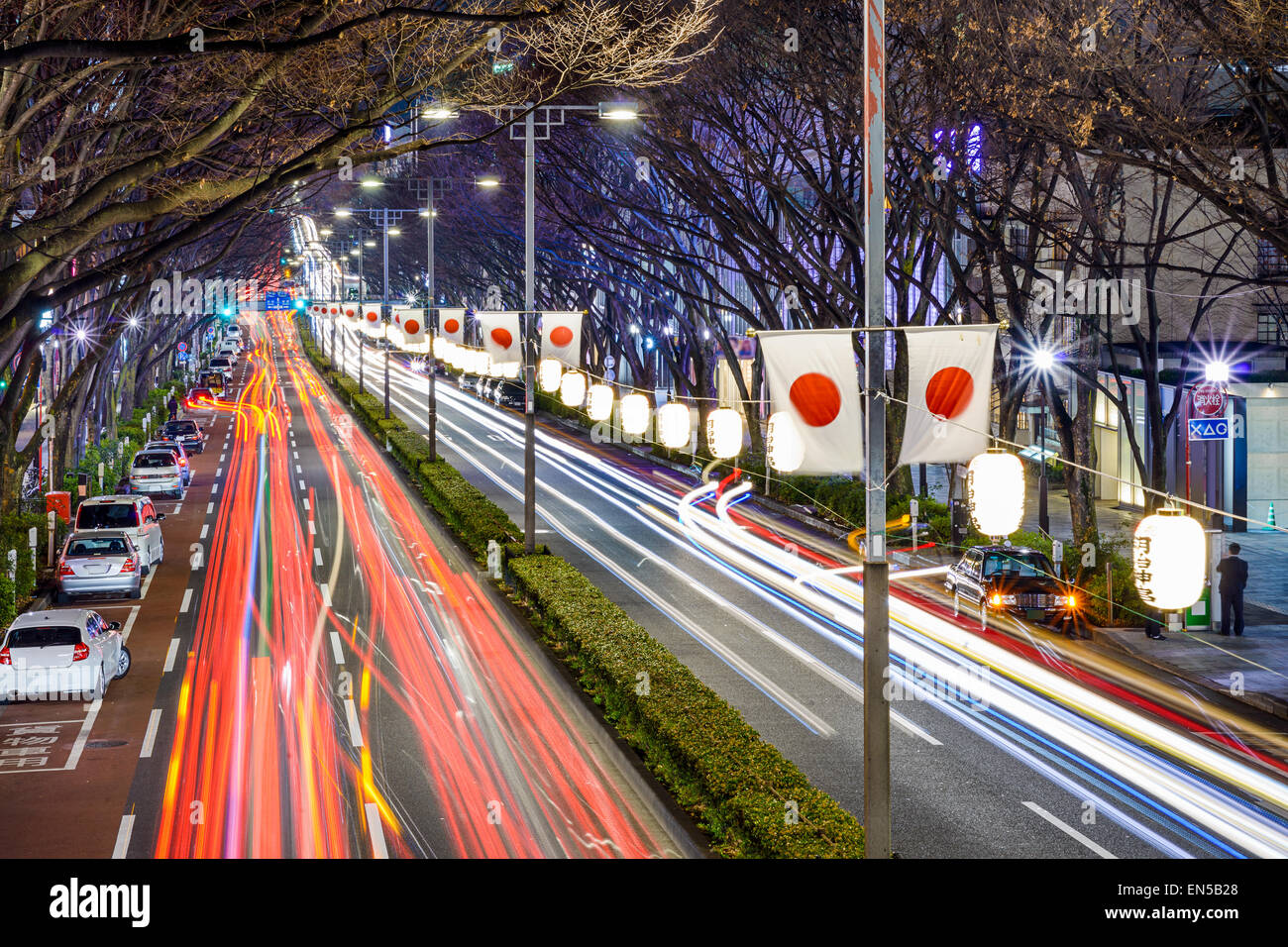Harajuku, Tokyo, Japan traffic flows below Japanese flags at night. Stock Photo
