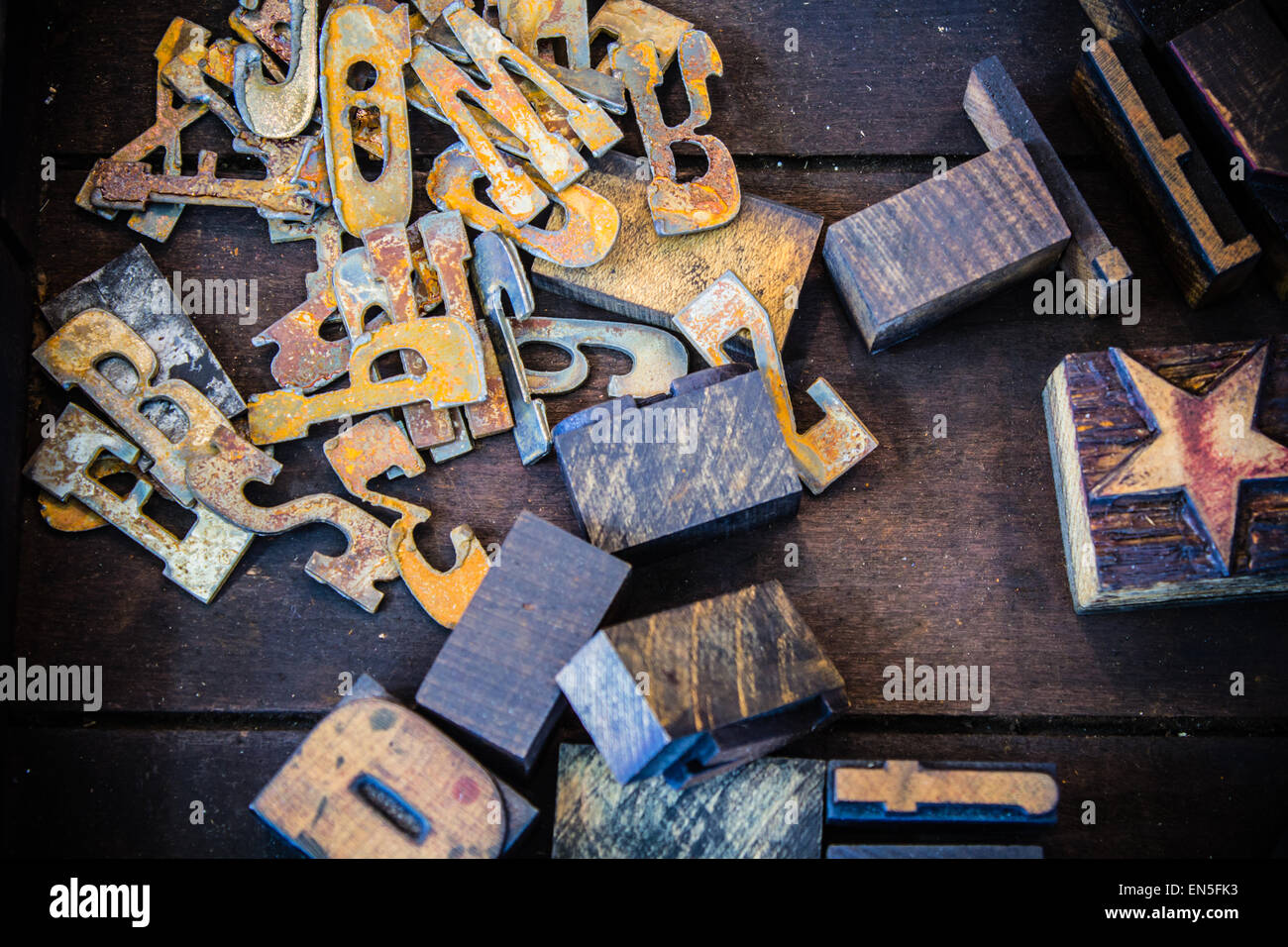 Rusty metal and vintage wooden letterpress numbers, letters, and star symbol inside a dirty wooden printer drawer. Stock Photo