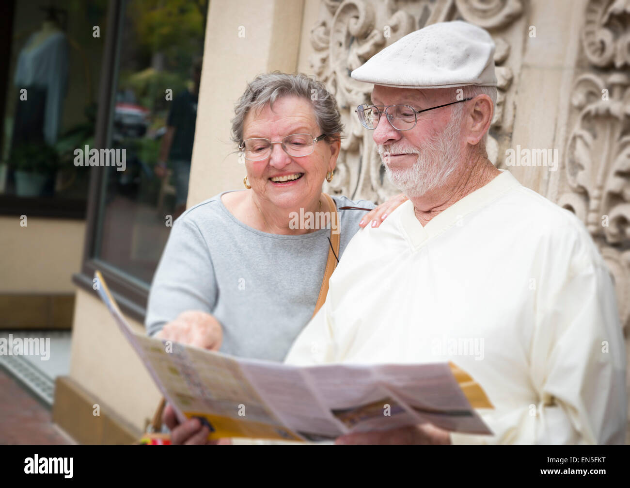 Happy Tourist Senior Couple Looking at Brochure Map. Stock Photo