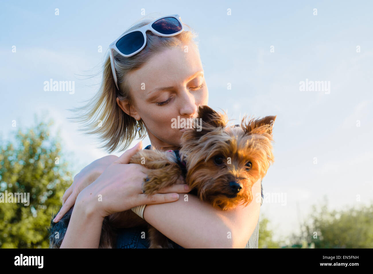 Beautiful Young Happy Woman With Blonde Hair Kissing Small Dog
