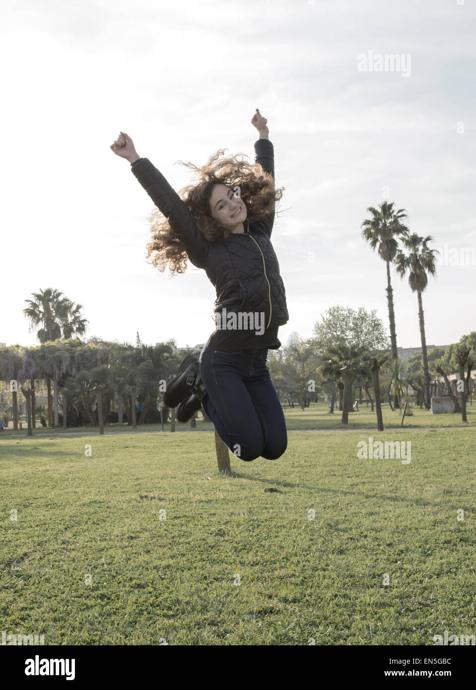 young girl smiling and jumping in the park Stock Photo - Alamy