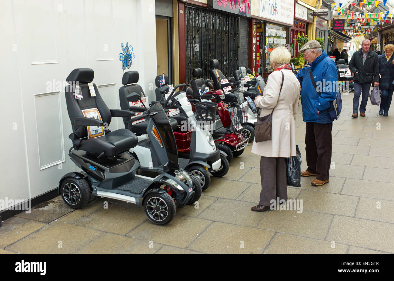 Older couple looking at mobility scooters in Southport Stock Photo