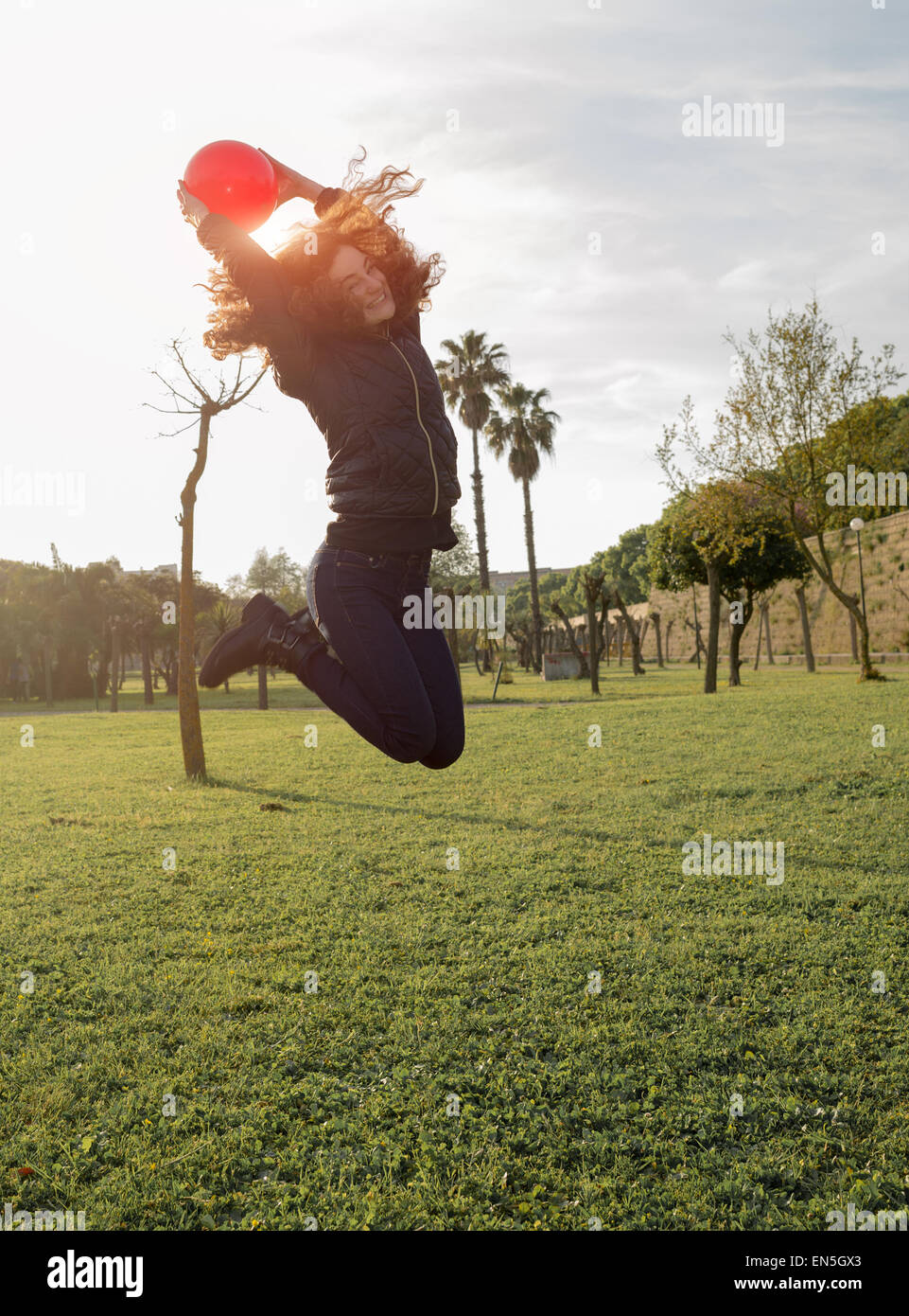 young girl smiling and jumping in the park Stock Photo - Alamy