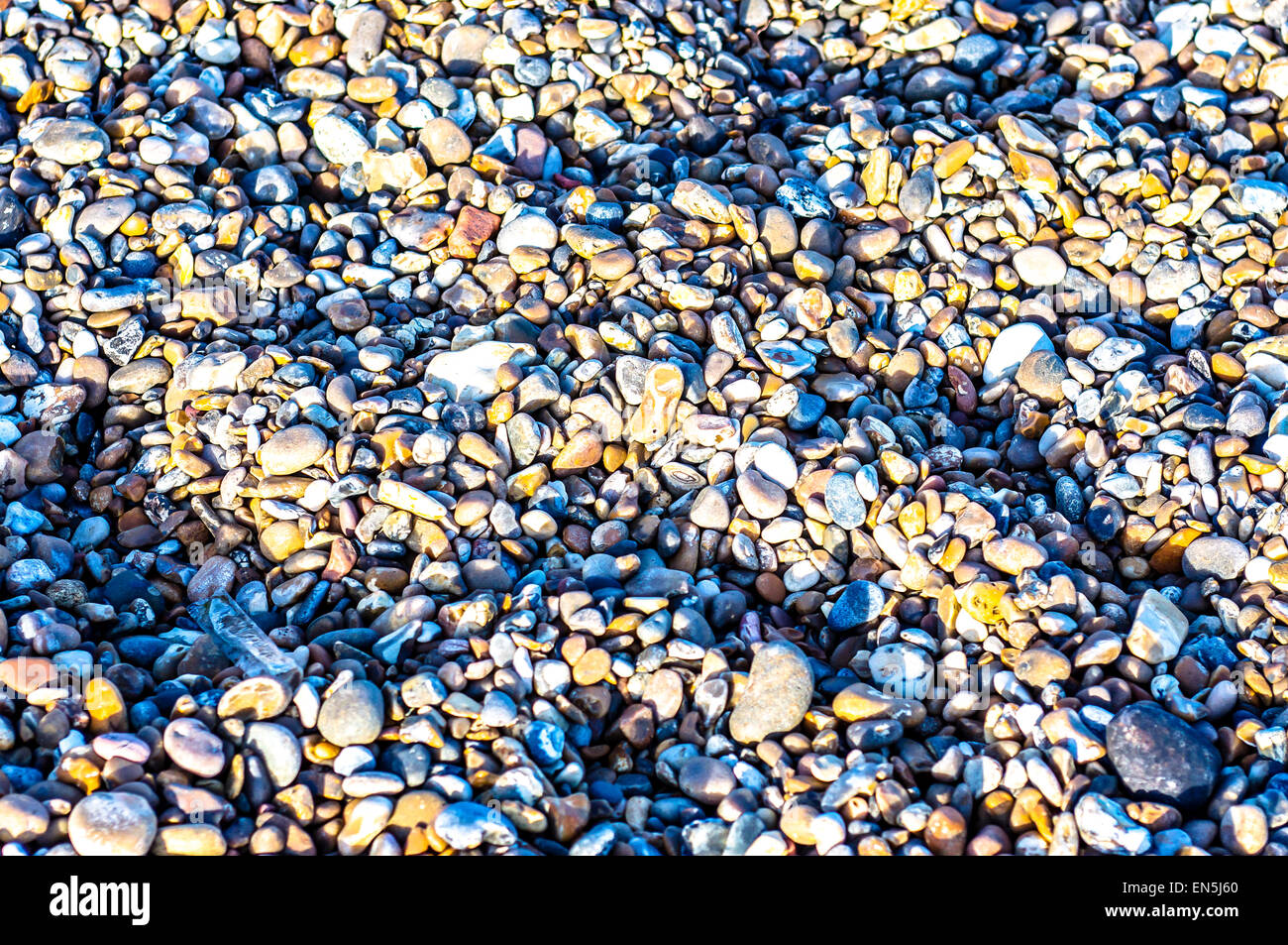 Close-up of the beautifully coloured pieces of stone comprising a gravel beach, sometimes called a shingle beach, in the UK. Stock Photo